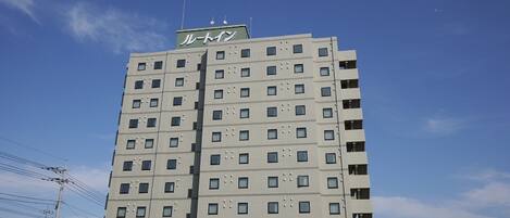 Un edificio de varios pisos con un letrero que dice "ルートイン" (Route In) en la parte superior.
