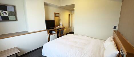 Une chambre d’hôtel équipée d’un lit, d’un bureau, d’une chaise, d’une télévision, d’un réfrigérateur et d’un miroir.