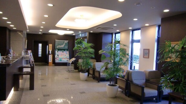 A modern lobby with a reception desk, seating area, and potted plants. - Hotel Route Inn Oyama (Oyama)