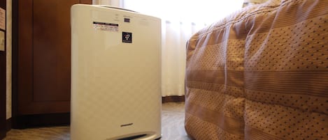 A room with a white air conditioner, a bed with a patterned cover, and a wooden door.