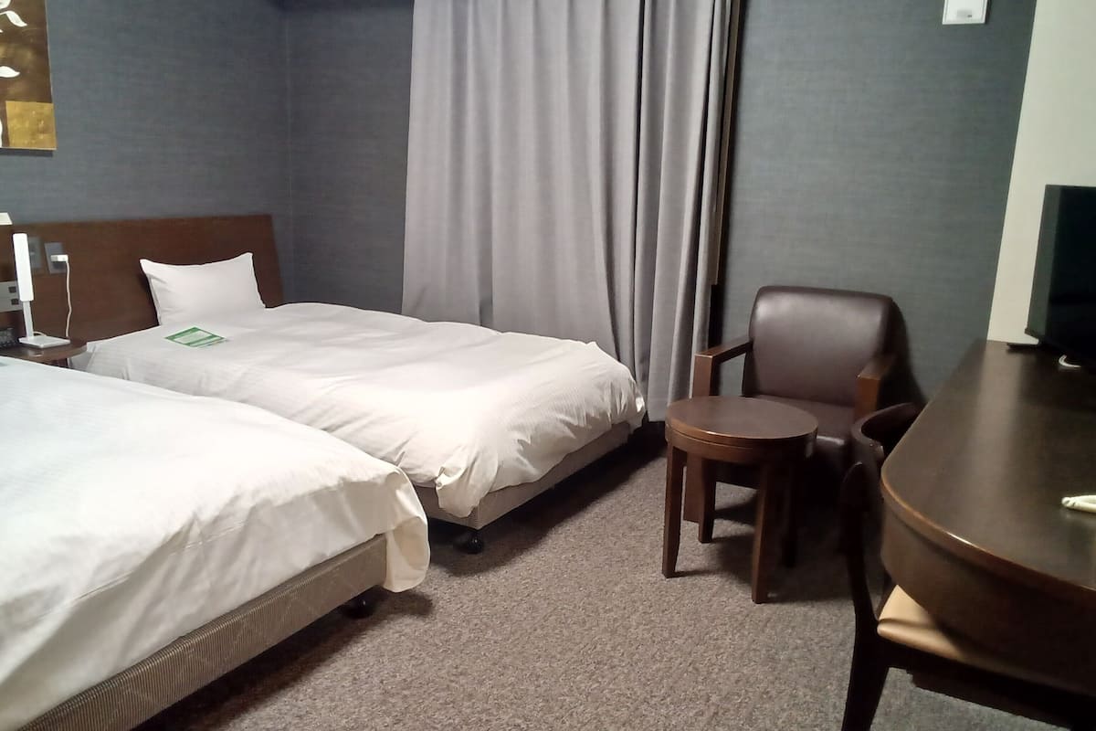 Une chambre d’hôtel avec deux lits, une chaise, une petite table et un téléviseur.