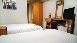 Une chambre d’hôtel avec deux lits, un bureau avec un ordinateur, une télévision et un petit réfrigérateur.