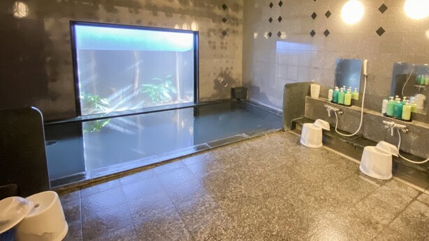 Une salle de bain moderne dotée d’une paroi de verre, d’un espace douche et d’un lavabo avec des articles de toilette.