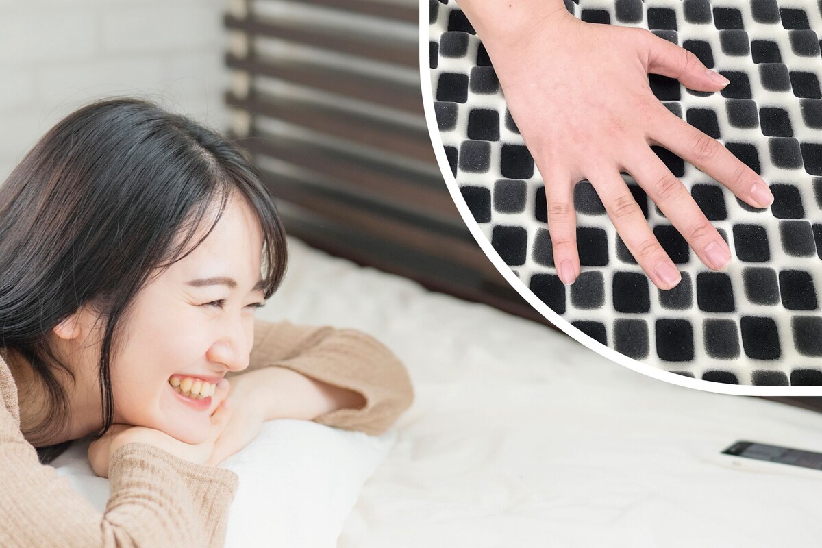 A person lying on a bed with a patterned pillow.