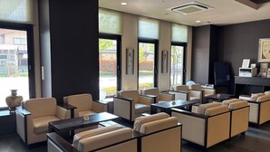 A modern hotel lobby with leather seating, large windows, and a flat-screen TV. - Hotel Route Inn Shibukawa (Shibukawa)