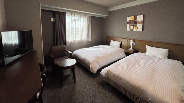 A hotel room with two beds, a TV, a desk, and a chair. - Hotel Route Inn Shibukawa (Shibukawa)