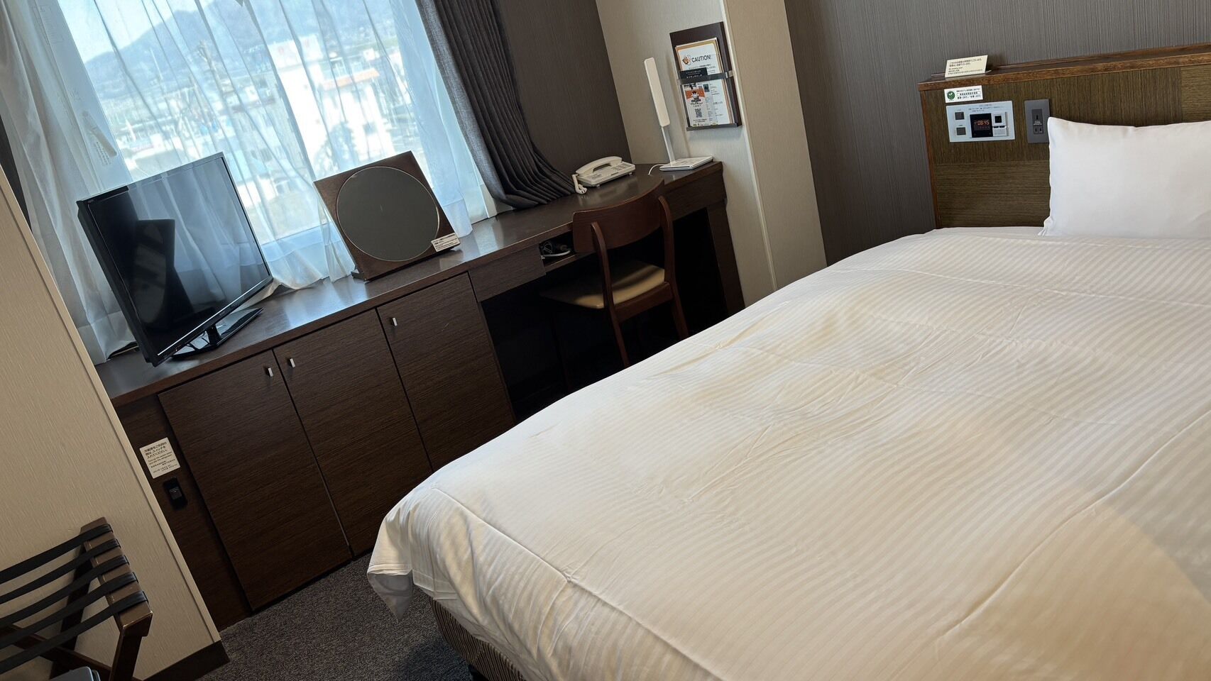 Une chambre d’hôtel comprenant un lit, un bureau avec un ordinateur portable, un téléphone et une table de chevet avec une lampe.