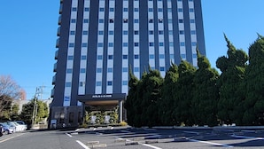 Un bâtiment d’hôtel au design moderne, avec une grande enseigne sur le toit et un parking à l’avant.