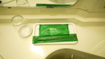 Ein Waschtisch mit einem grünen Produkt, beschriftet mit „ROUTE INN HOTELS“, und einem klaren Glas.