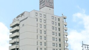 A multi-story hotel with a prominent sign at the top, multiple balconies, and a parking area in front. - Hotel Route Inn Takasakieki Nishiguchi (Takasaki)