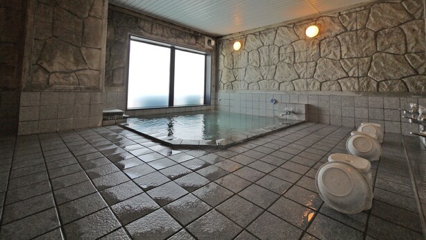 A stone-walled indoor pool with a tiled floor and a large window. - Hotel Route Inn Takasakieki Nishiguchi (Takasaki)