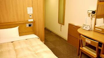 Een hotelkamer met een bed, een bureau met een spiegel, een telefoon en een klein kastje.