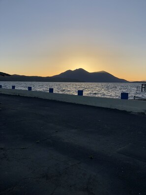 A paved walkway beside a body of water with a mountain in the background. - Lamplighter Motel (Clearlake)