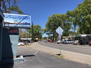 Un hôtel appelé « Lamplighter Inn », avec une enseigne indiquant « CHAMBRES LIBRES », une route bordée de voitures garées et un magasin appelé « Turf & Collective ».