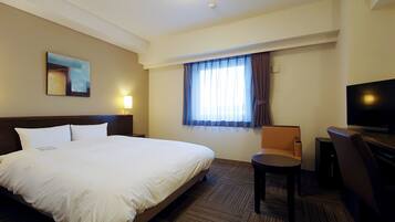 Een hotelkamer met een groot bed, een bureau met stoel, een televisie en een raam met gordijnen.