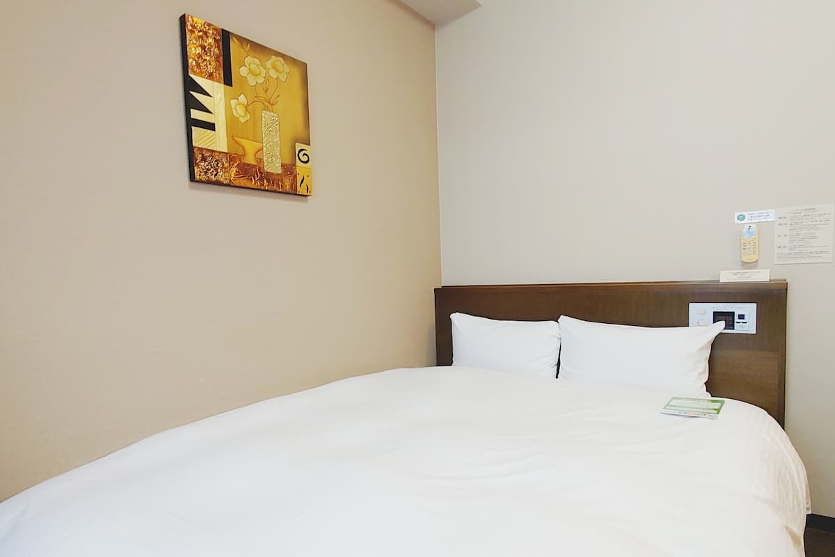 Quarto de hotel com uma cama grande, cabeceira de madeira e um quadro na parede.