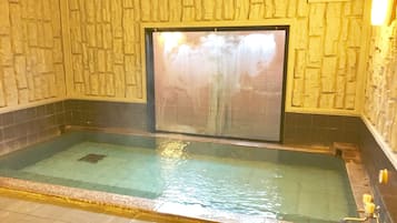 Un jacuzzi con un fondo de pared de piedra y una ventana.