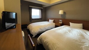 Une chambre d’hôtel avec deux lits, un bureau, une télévision, une lampe et une fen être avec des rideaux.