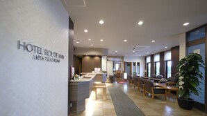 A hotel lobby with a reception desk, seating area, and large windows.
