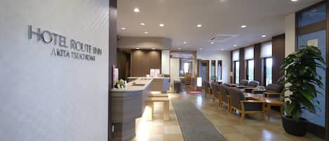 A hotel lobby with a reception desk, seating area, and large windows.