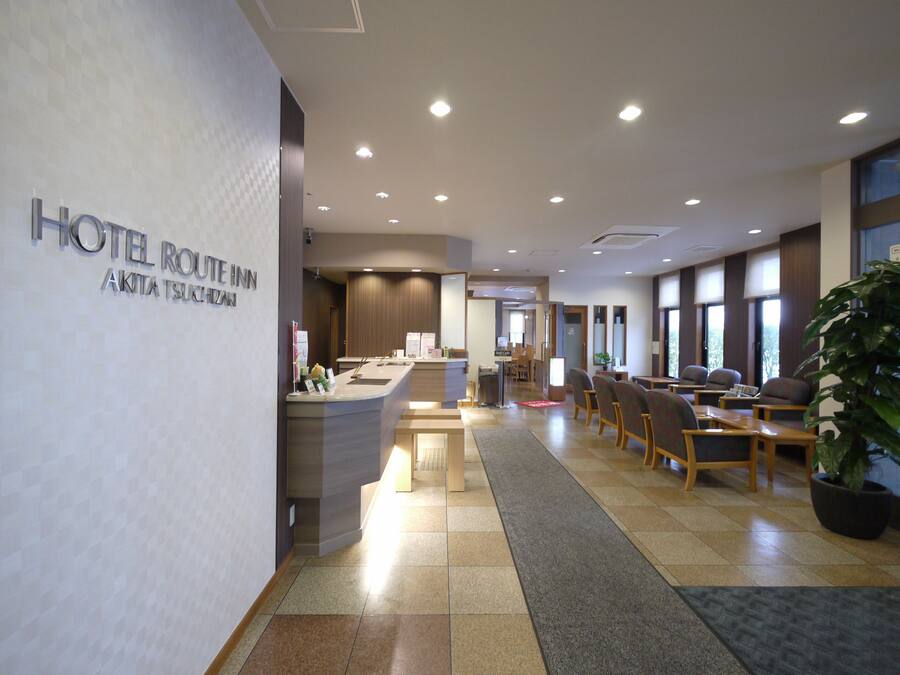 A hotel lobby with a reception desk, seating area, and large windows.