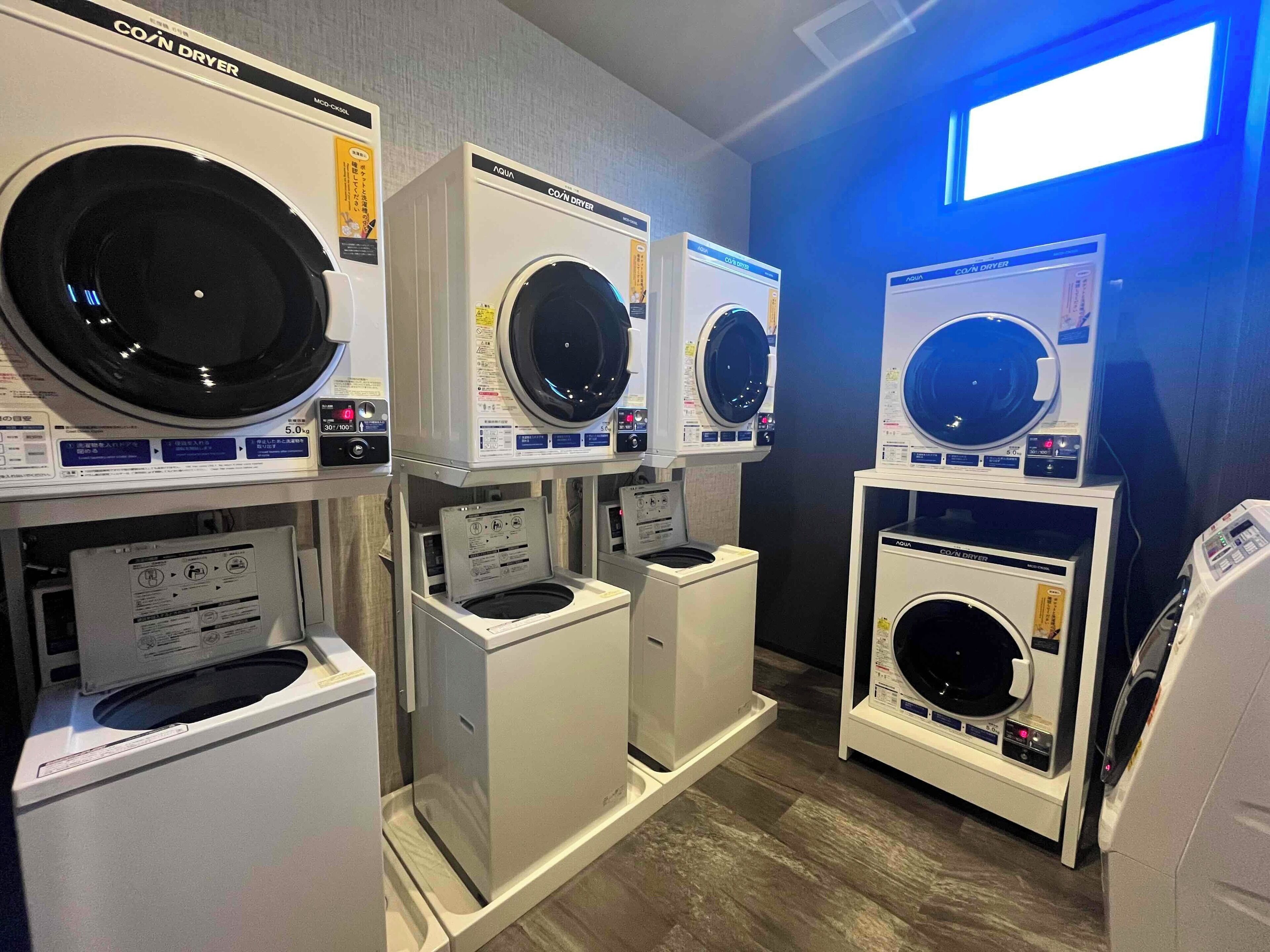 A laundry facility with multiple washing machines and dryers, including a front-loading washer and a top-loading dryer.