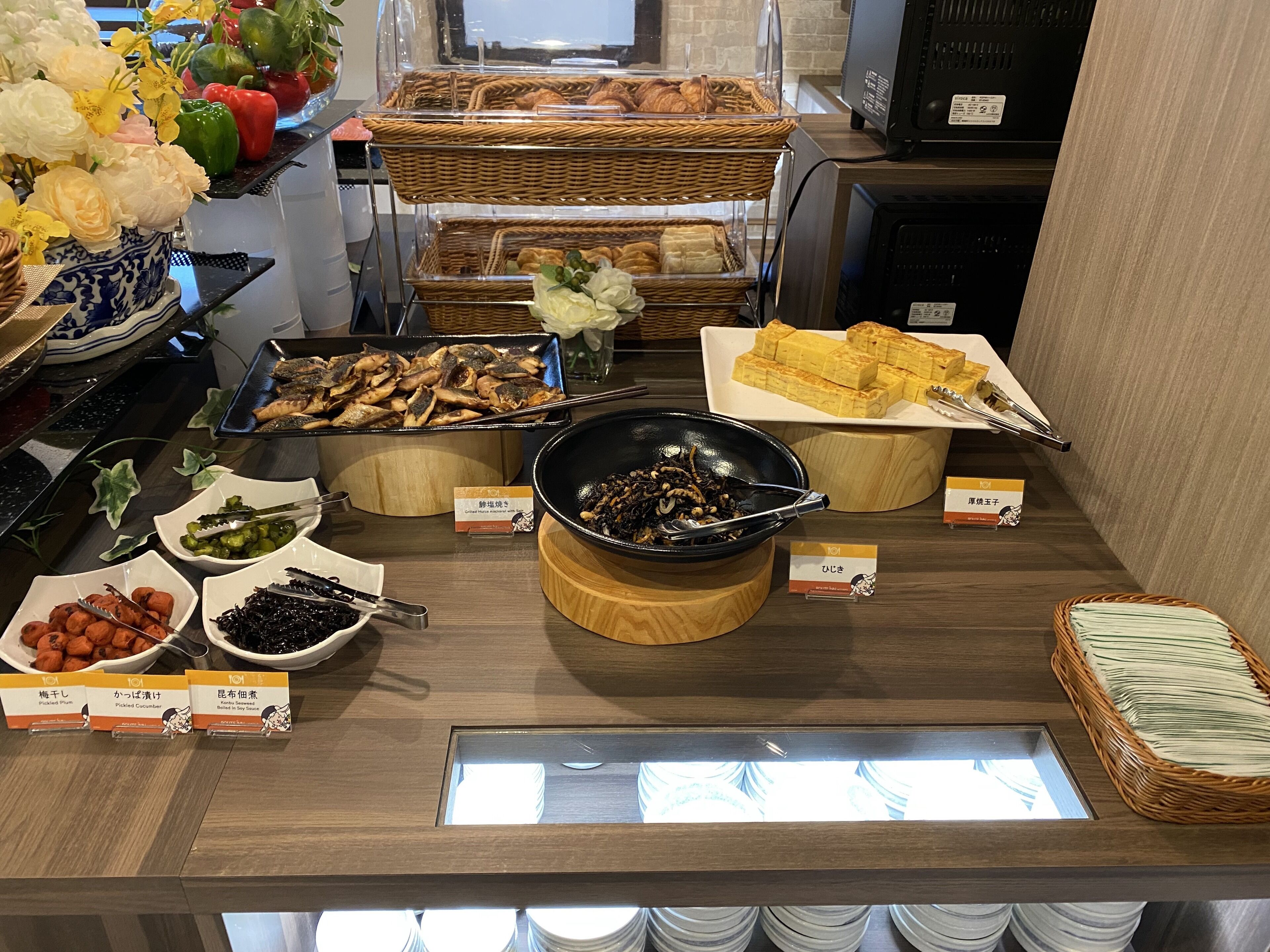 Mostrador de buffet con diferentes alimentos, como pepinos encurtidos, setas rellenas y pan.