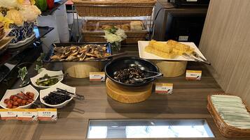 Mostrador de buffet con diferentes alimentos, como pepinos encurtidos, setas rellenas y pan.