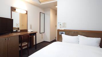 A hotel room with a bed, a desk, a chair, a television, a mirror, and a wall-mounted phone.