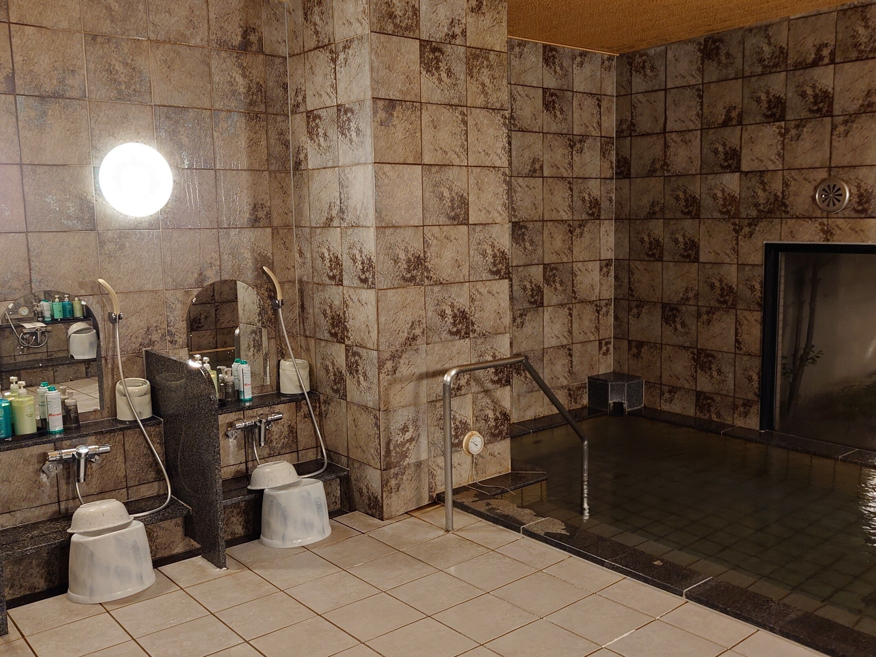 A bathroom with a shower, a sink with toiletries, and a mirror.