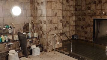 A bathroom with a shower, a sink with toiletries, and a mirror.