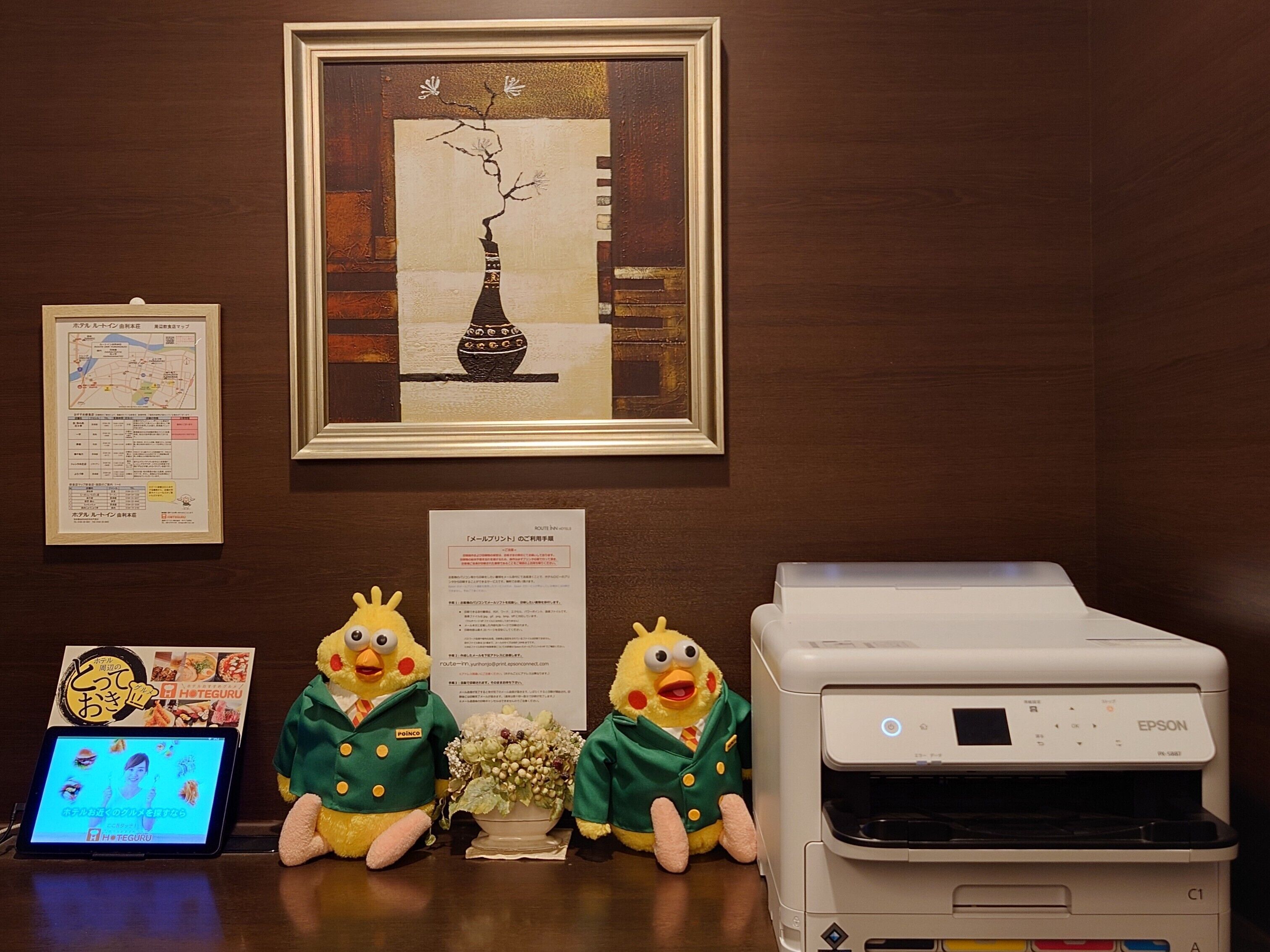 A reception desk with a framed artwork, a map, and a printer.