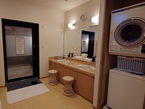 A hotel bathroom with a sink, mirror, and a washing machine.
