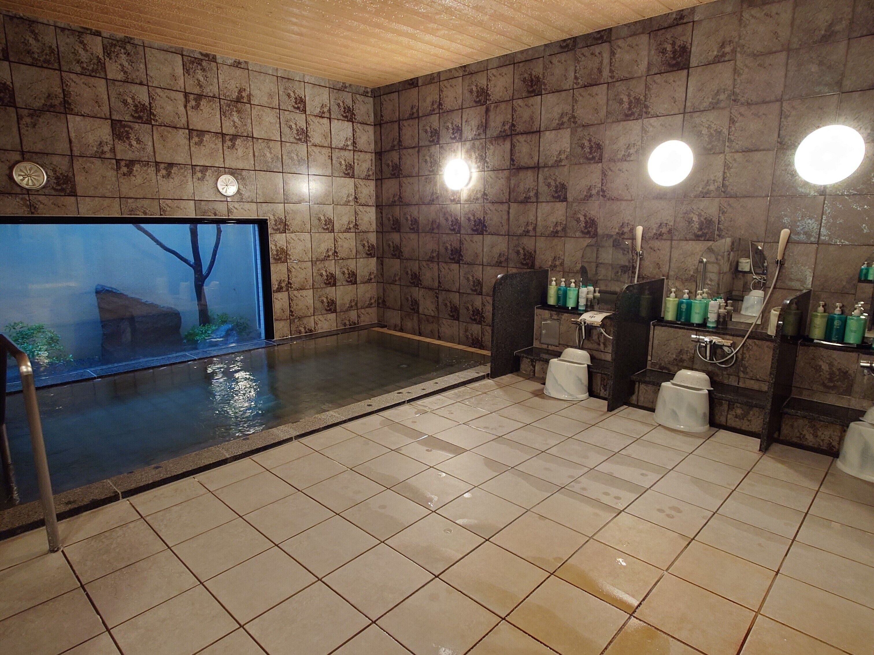 A spa room with a large bathtub, a wooden ceiling, and a tiled floor.