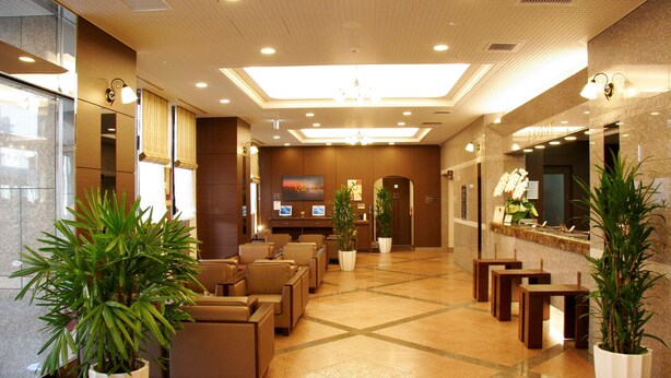 A hotel lobby with seating areas, a reception desk, and potted plants. - Hotel Route-Inn Ichinoseki Inter (Ichinoseki)