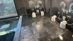 A modern bathroom with dark tiled walls, a wet floor, and multiple sinks with mirrors. - Hotel Route-Inn Ichinoseki Inter (Ichinoseki)