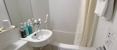 A bathroom with a white sink, mirror, and shower curtain. There are toiletries on the sink and a towel hanging on the wall.