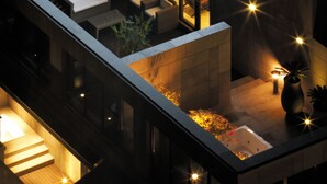 Un hotel moderno con un cartel iluminado llamativo, una zona de estar al aire libre y un interior bien iluminado.
