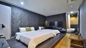 Habitación de hotel moderna con una cama grande, un televisor de pantalla plana, un escritorio y un baño con bañera.