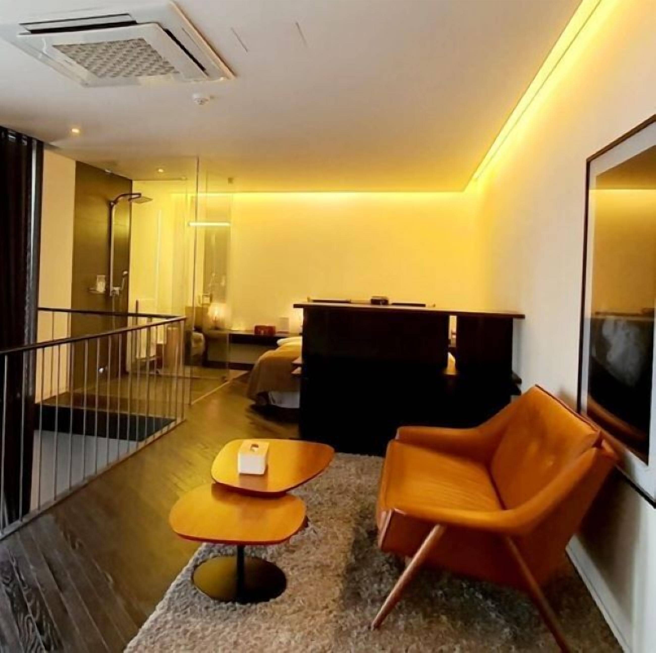 Una habitación de hotel moderna con zona de estar, una pequeña mesa y un televisor.