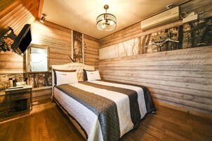 Un dormitorio acogedor con una cama grande, paredes de madera y una lámpara de araña.