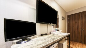 A kitchenette with a wooden countertop, two black monitors, a small refrigerator, and a wooden door. - Q Hotel (Yongin)