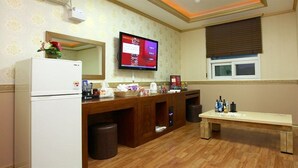 A hotel bathroom with a wooden vanity, a refrigerator, a television, and a window with blinds. - Q Hotel (Yongin)