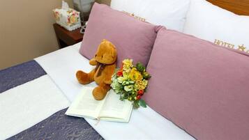A bed with a teddy bear, a bouquet of flowers, and a book.