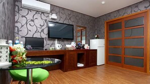 A compact kitchen with a TV, a refrigerator, and a wooden cabinet. - Q Hotel (Yongin)