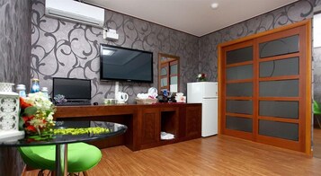 Una cocina compacta con un televisor, un refrigerador y un armario de madera.