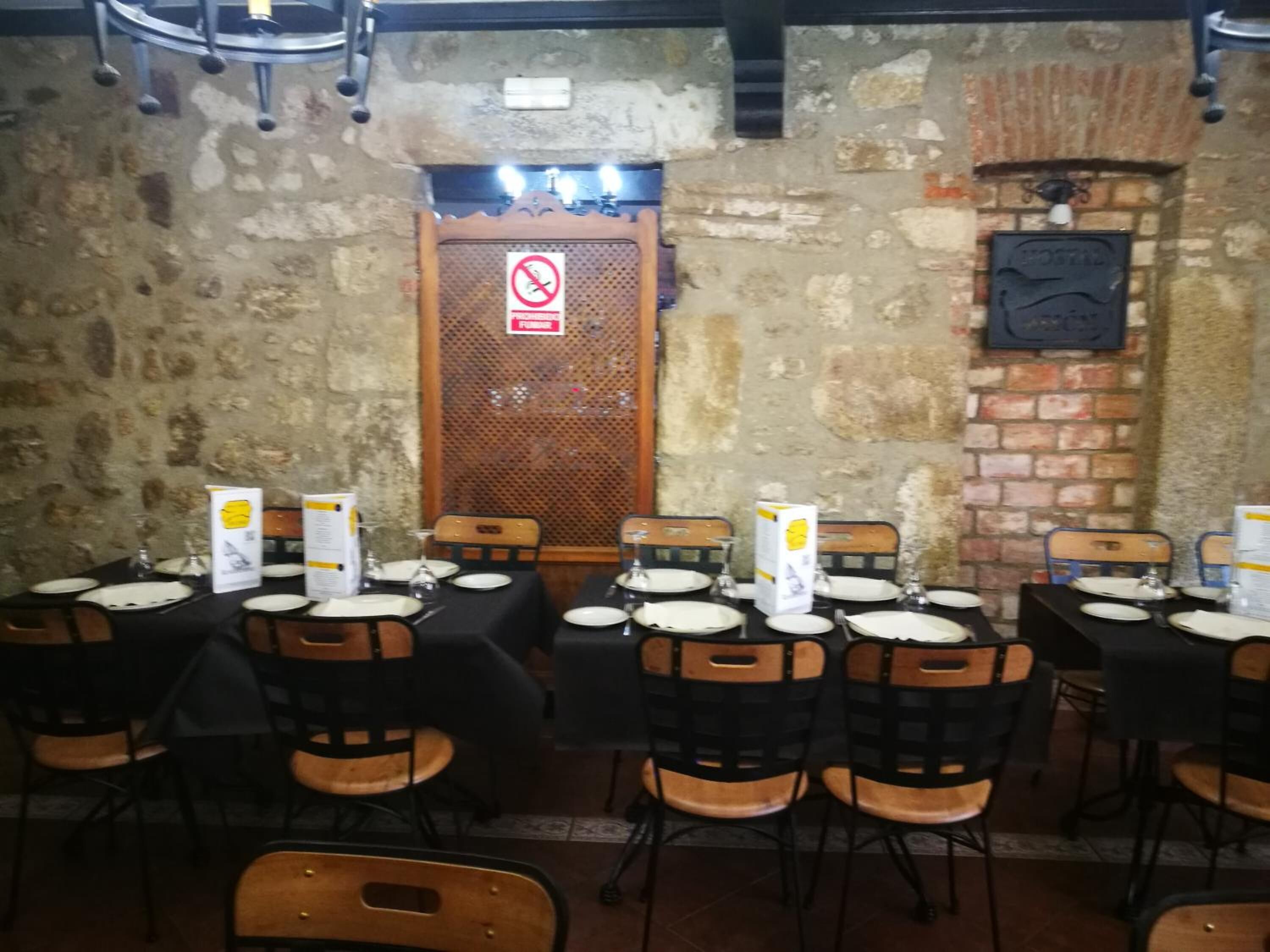 Un restaurante con mesas dispuestas para comer, sillas y un fondo de pared de ladrillo.