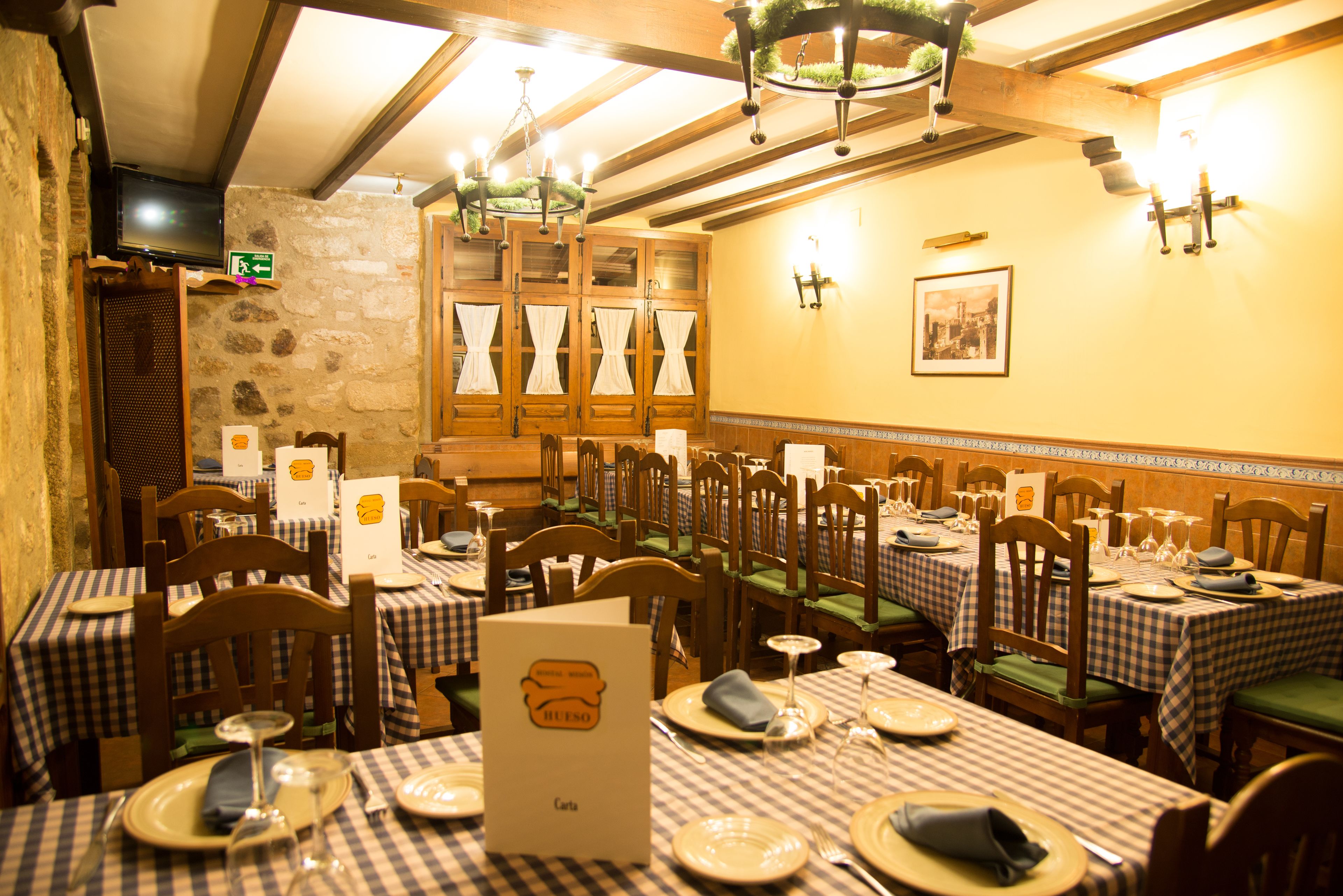 Un restaurante con manteles a cuadros, sillas de madera y una pared de piedra.