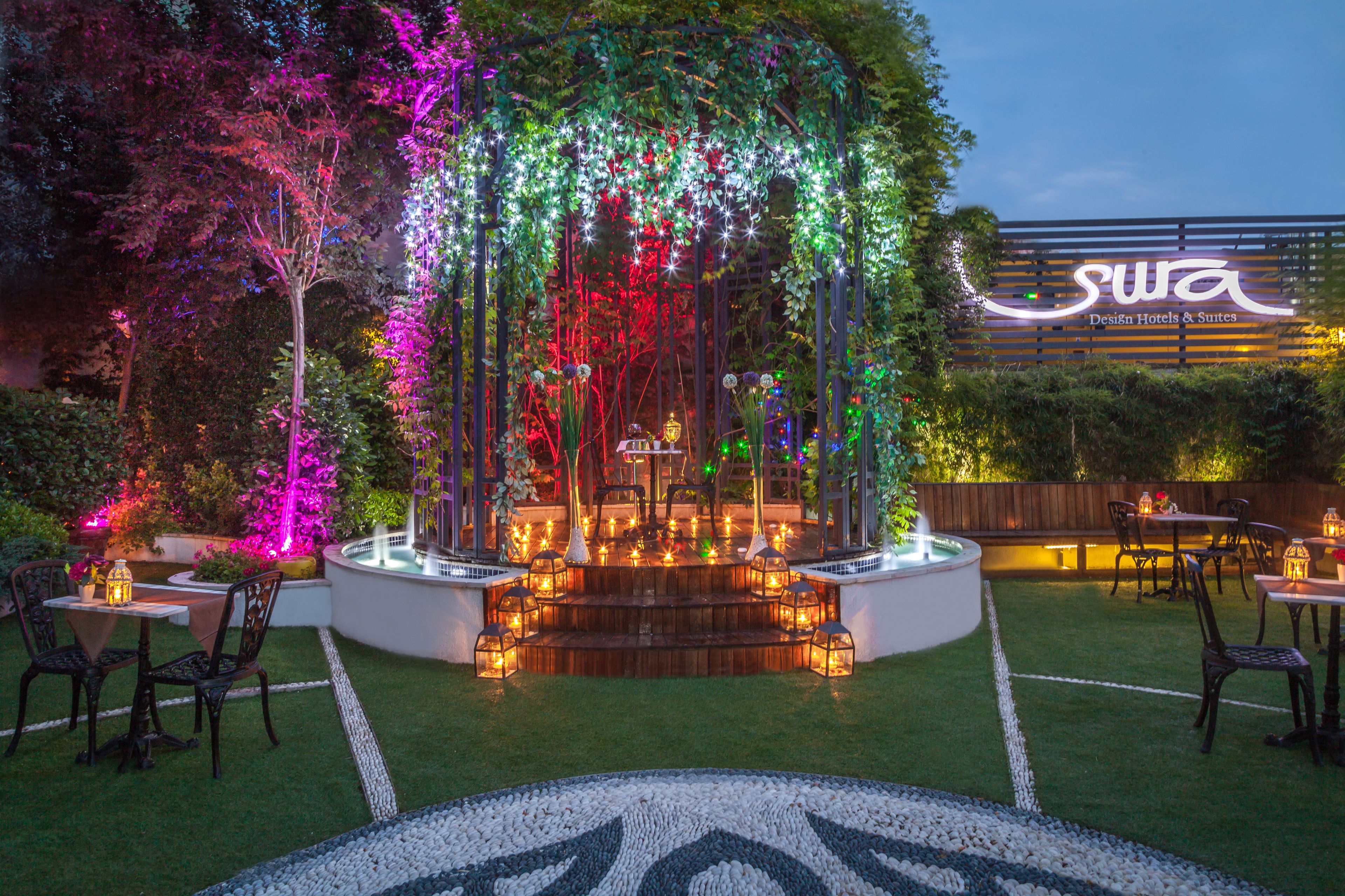 An outdoor garden area with a fountain, seating, and a sign for 'Sura Design Hotels & Suites'.