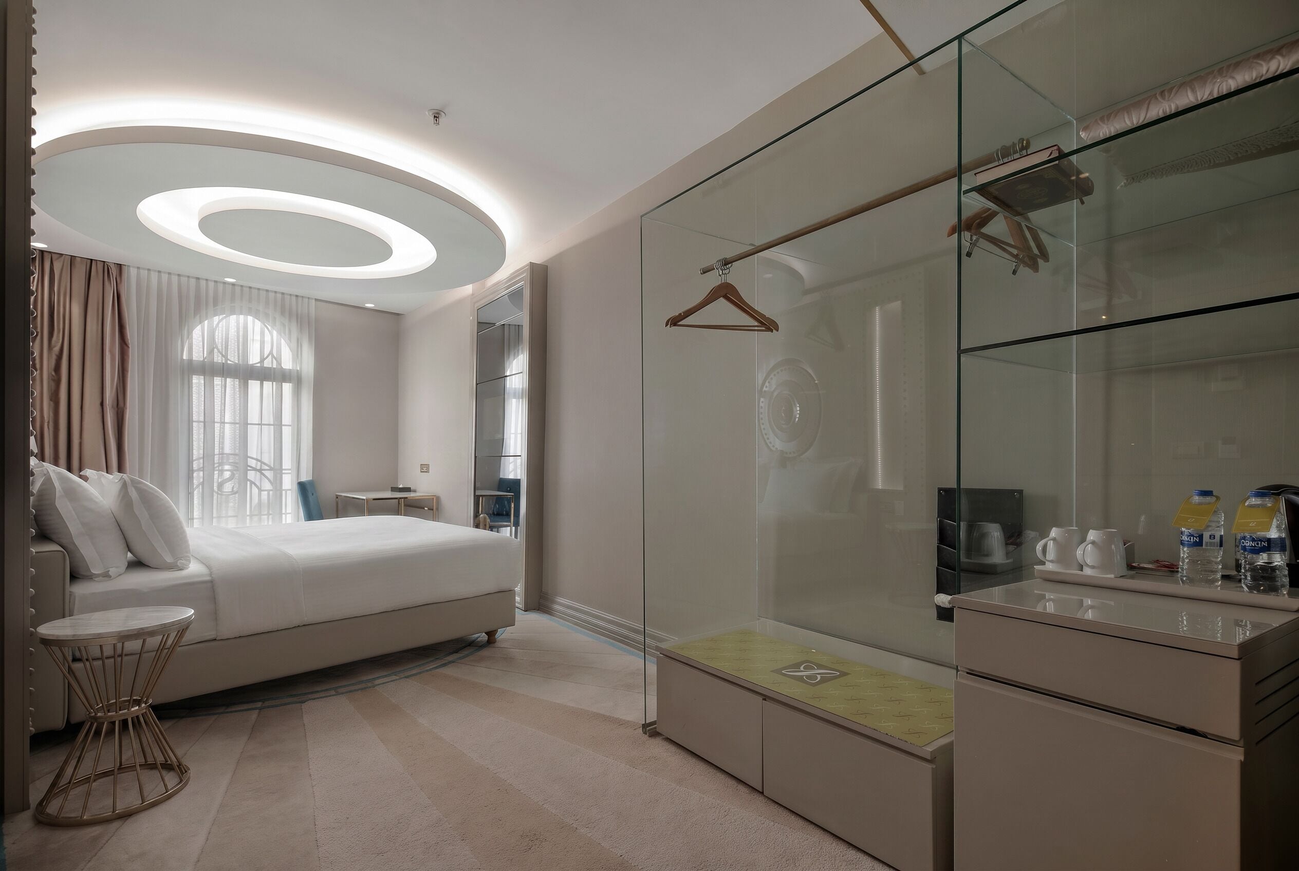 Ein modernes Schlafzimmer mit Bett, Nachttisch und einem begehbaren Kleiderschrank mit Glastüren.